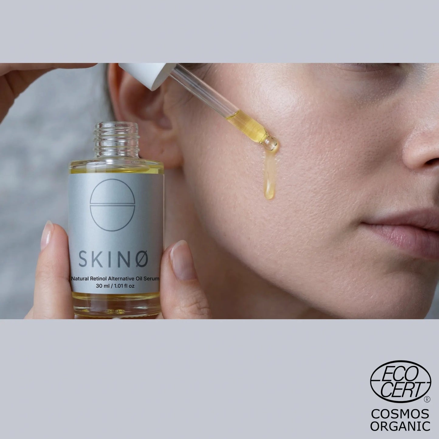 Kvinna applicerar droppe SKINØ Bakuchiol Oil Serum på kinden – naturligt retinolalternativ för fastare och förnyad hud, gyllene olja med bakuchiol och nyponolja, ECOCERT COSMOS ORGANIC.