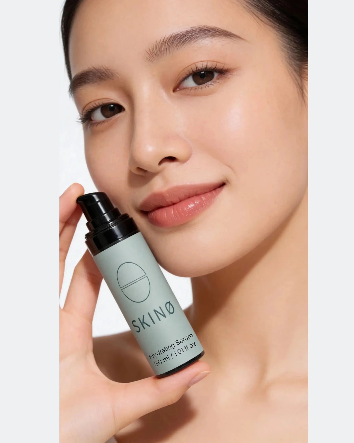 Kvinna håller SKINØ Hydrating Serum 30 ml mot ansiktet – intensiv fuktboost med hyaluronsyra och hjortron för strålande, mjuk och återfuktad hud, naturligt ansiktsserum för torr och känslig hud, COSMOS ORGANIC.